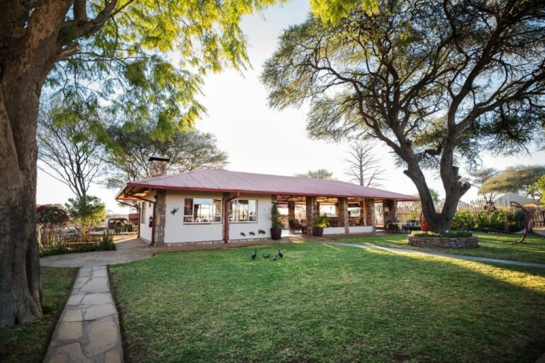 Farmhouse with a red roof under large trees at Dornhuegel Guest Farm