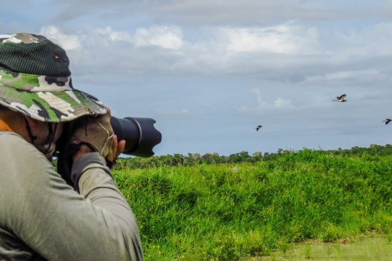 Etosha photography guide planning represented by a wildlife photographer using a long lens in the field